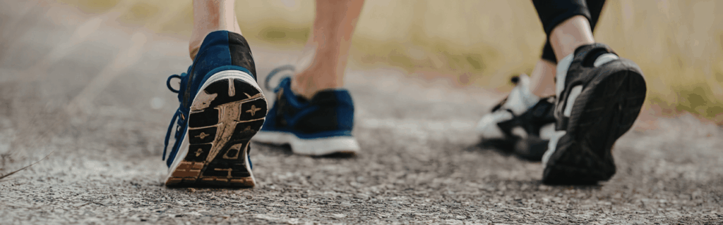 Image of two people's feet walking in sneakers